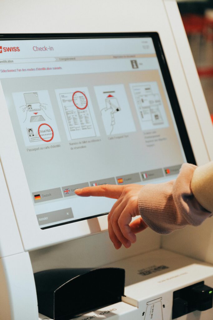 Person in Brown Long Sleeve Shirt Using Self Service Check in Kiosk