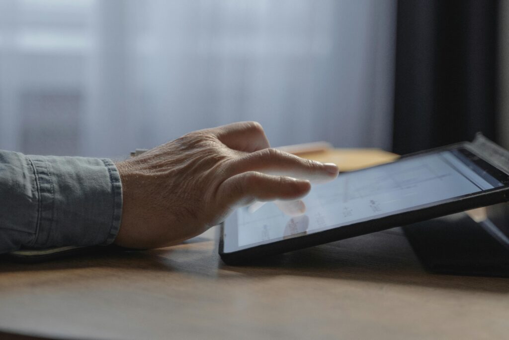 A person's hand interacting with a digital tablet onscreen indoors, close-up view.