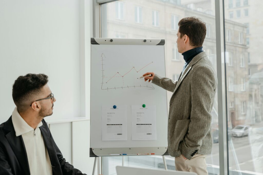 Two professionals examining graphs during an office presentation.